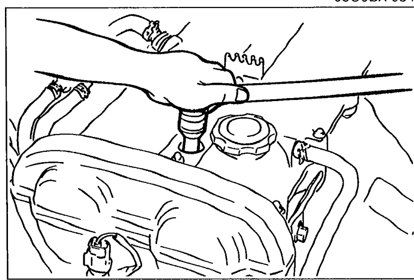 View of cylinder head area showing spark plug location with hand-held tool applying lubricant to spark plug threads.
