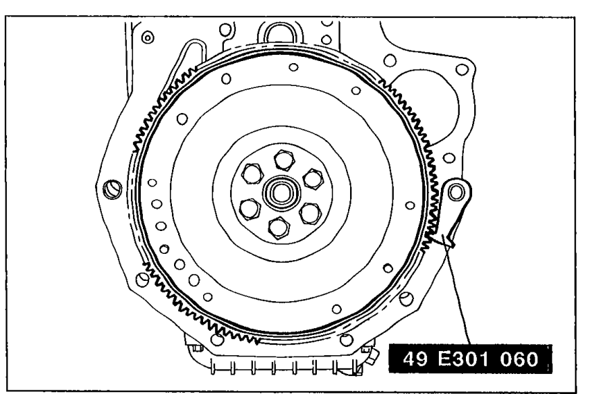 Removing the flywheel with SST 49 E301 060 holding it in place. Shows the flywheel and SST mounted at the bottom of the engine.
