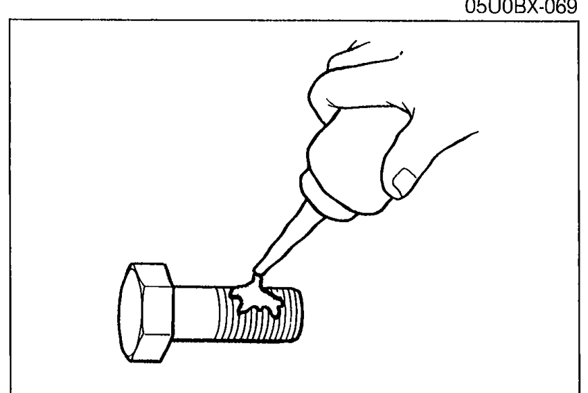 Applying sealant to a flywheel bolt with a tube/applicator before installing.