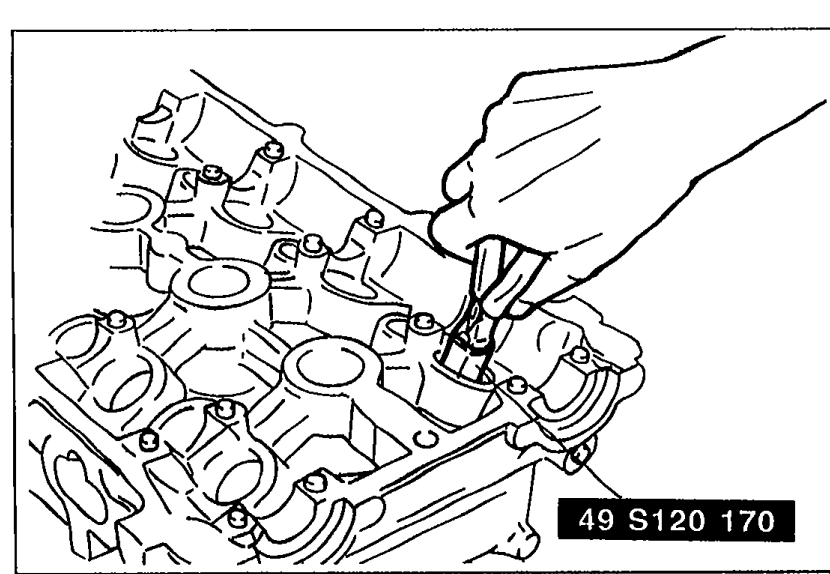 Cylinder head shown with a hand using SST 49 S120 170 (valve seal remover) pliers to grip and remove a valve seal from the valve guide.