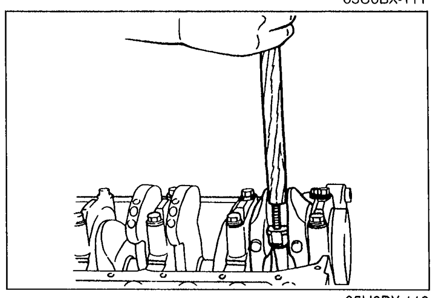 Using the handle of a hammer to drive the piston and connecting rod assembly out through the top of the cylinder block.