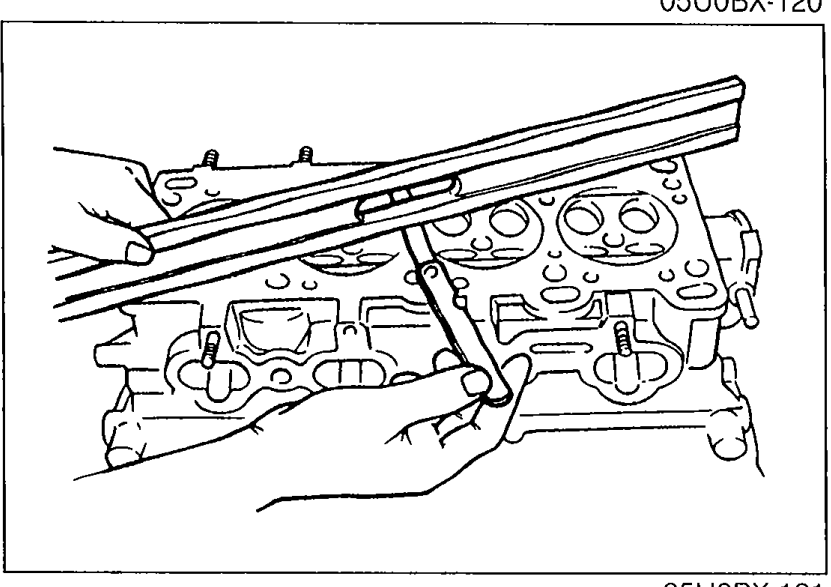 Side view of the cylinder head with a straight edge laid along the deck face, used for grinding/height measurement.