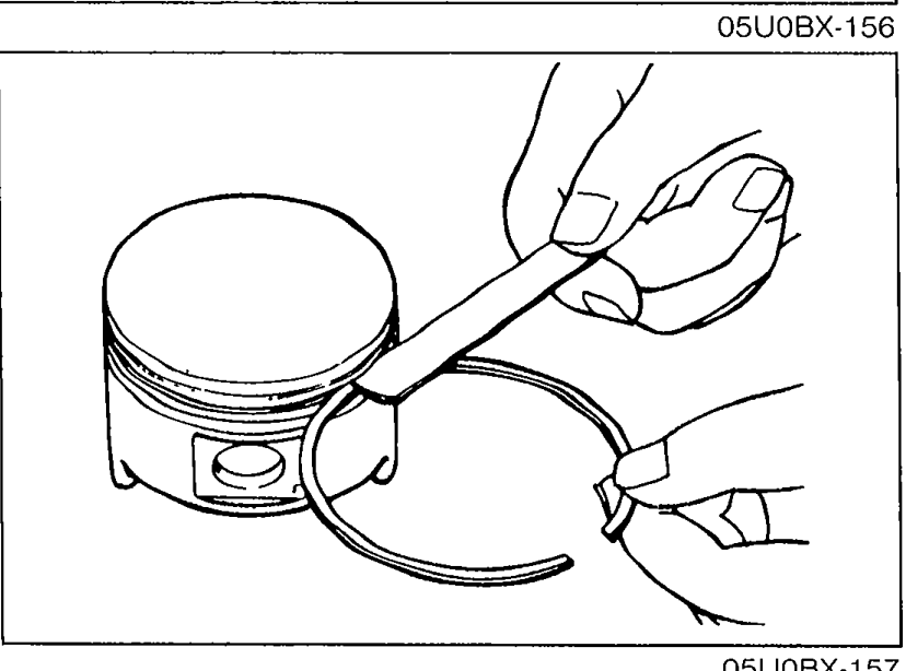 Hand holding a piston with a new piston ring being used as a feeler gauge to measure the ring-to-ring-land clearance around the circumference.