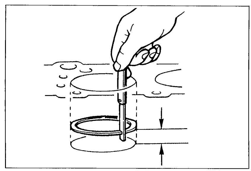 Hand using a feeler gauge to measure the end gap of a piston ring inside a cylinder bore (top view).