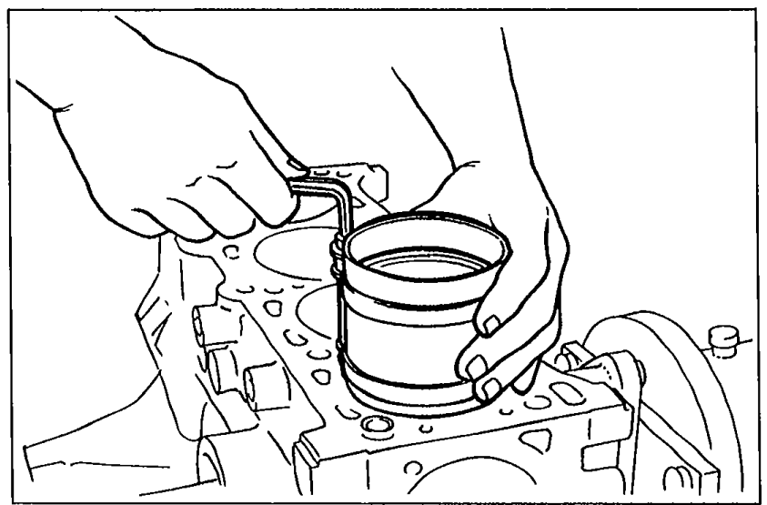 Piston ring compressor and piston assembly being inserted into a cylinder bore in the engine block.