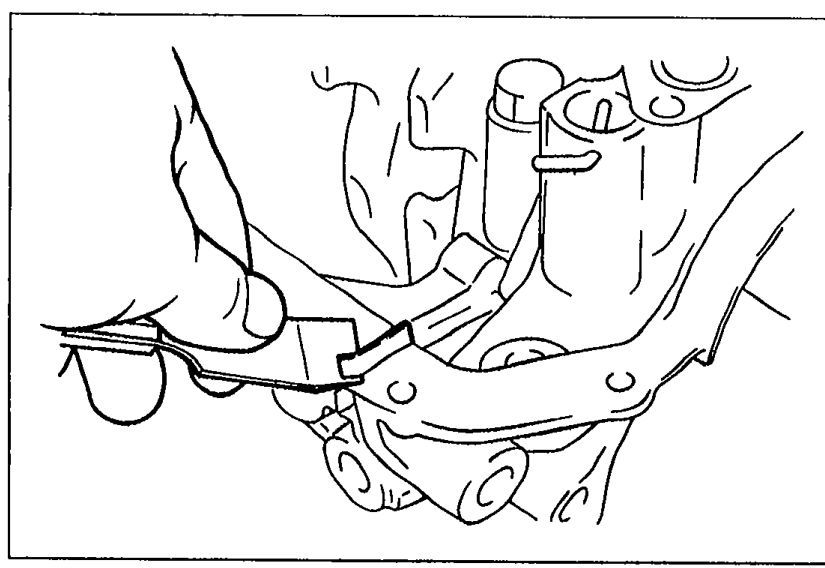 A hand using a cutting tool to trim the excess oil pump gasket protruding from the body toward the oil pan side.