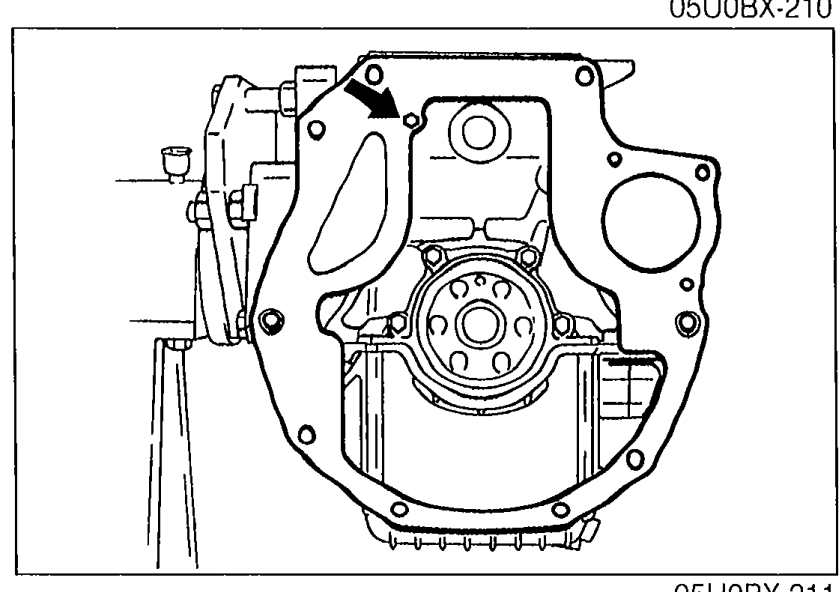 End plate installed on the rear of the engine with an arrow pointing to the mounting location. Crankshaft rear flange visible in center.