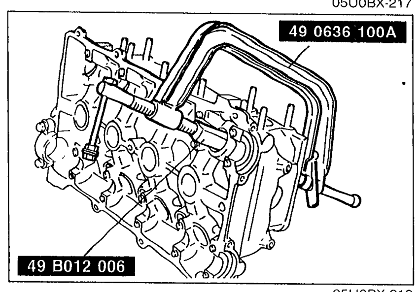 Valve spring compressor SSTs 49 0636 100A and 49 B012 006 in use on the cylinder head, compressing valve springs to install/remove valve keepers.