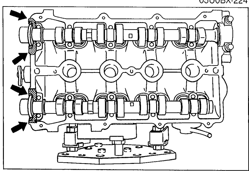 Cylinder head with camshafts installed; arrows along the left side indicate the shaded areas where silicone sealant must be applied at the cam cap mating surfaces.