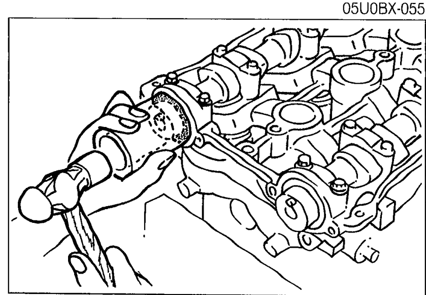 New camshaft oil seal being tapped into place with a suitable pipe and hammer on the front of the camshaft, with the oil seal seated against the camshaft cap.