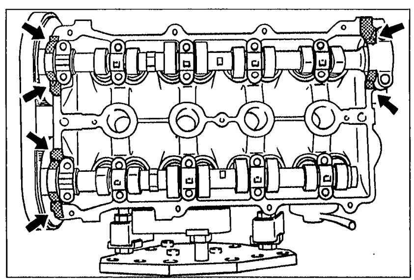 Top view of the cylinder head with the cover removed, showing the camshafts. Shaded areas with arrows at the corners indicate where silicone sealant should be applied before installing the cylinder head cover.