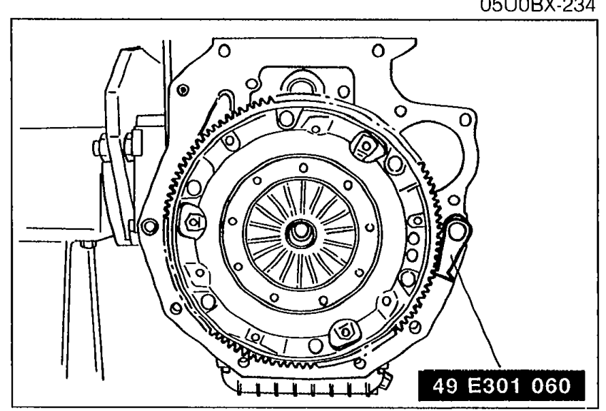 SST (49 E301 060) installed on the flywheel/crankshaft pulley area to hold it while tightening the lock bolts. Tool number label '49 E301 060' visible at the bottom.