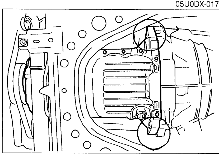 Photograph of the oil pan being pried loose from the cylinder block using a screwdriver at the indicated points.