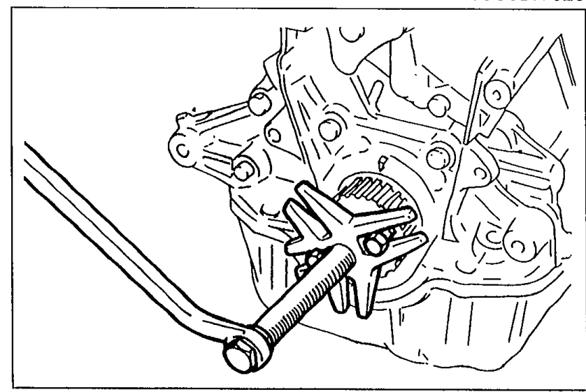 Photograph showing a steering wheel puller engaged on the timing belt pulley to remove it.