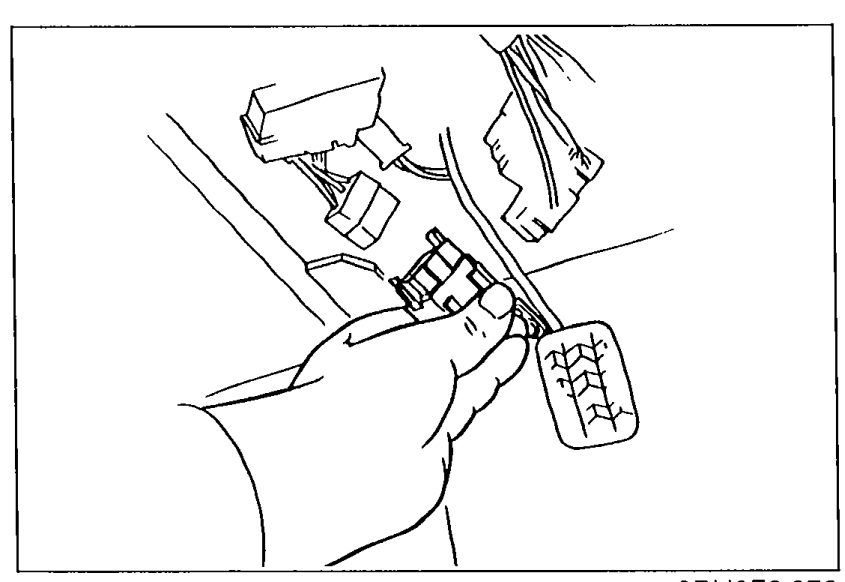 Hand disconnecting the circuit opening relay connector in the engine bay.