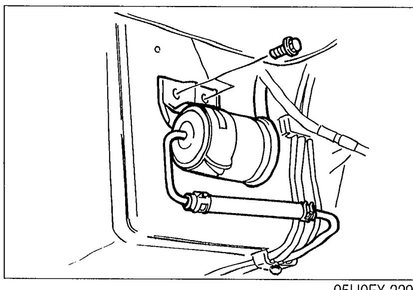 Underside photograph showing the fuel filter assembly with hoses still connected — removed from its bracket.