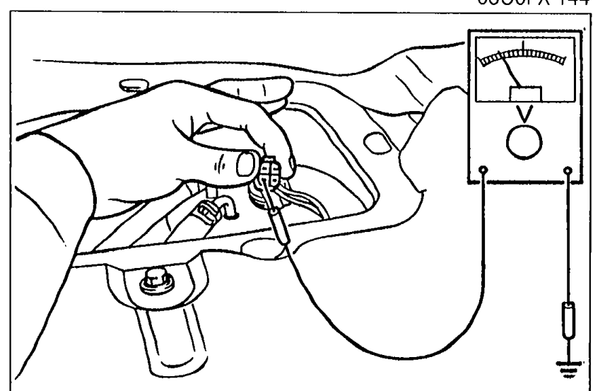 Photo of a hand using a voltmeter at the fuel filler area to listen for / verify fuel pump operation.