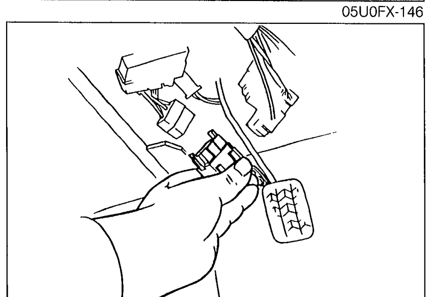 Photo of the fuel pump connector being disconnected at the rear of the vehicle to release fuel pressure prior to inspection.
