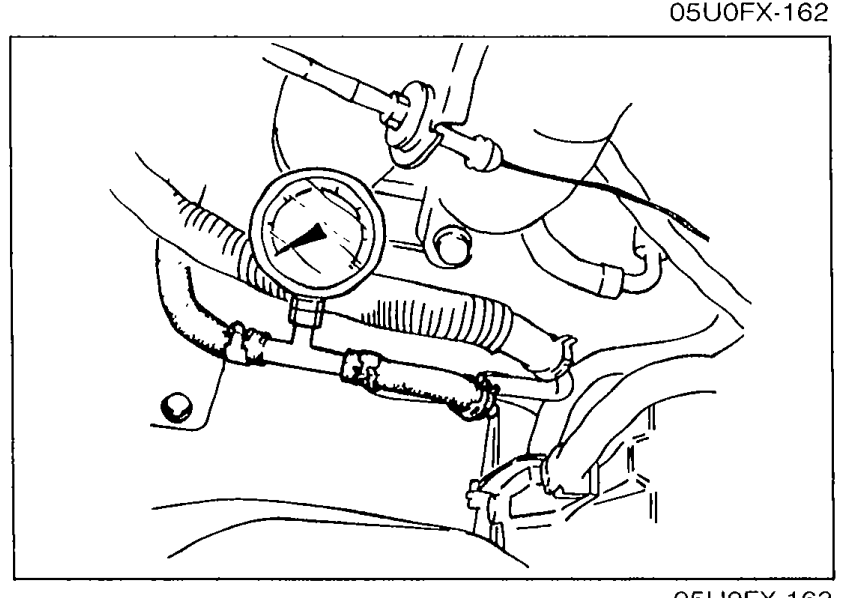 Photo of a fuel pressure gauge installed between the fuel main pipe and the fuel hose with clamps, for measuring fuel line pressure at idle.