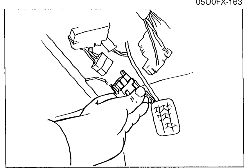 Photo of a hand disconnecting the fuel pump connector at the rear of the vehicle, illustrated for the hold-pressure inspection procedure.