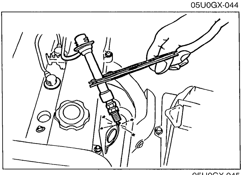 Spark test setup: high-tension lead connected to a new spark plug held with insulated pliers approx. 5–10 mm from a ground point on the engine, while cranking.