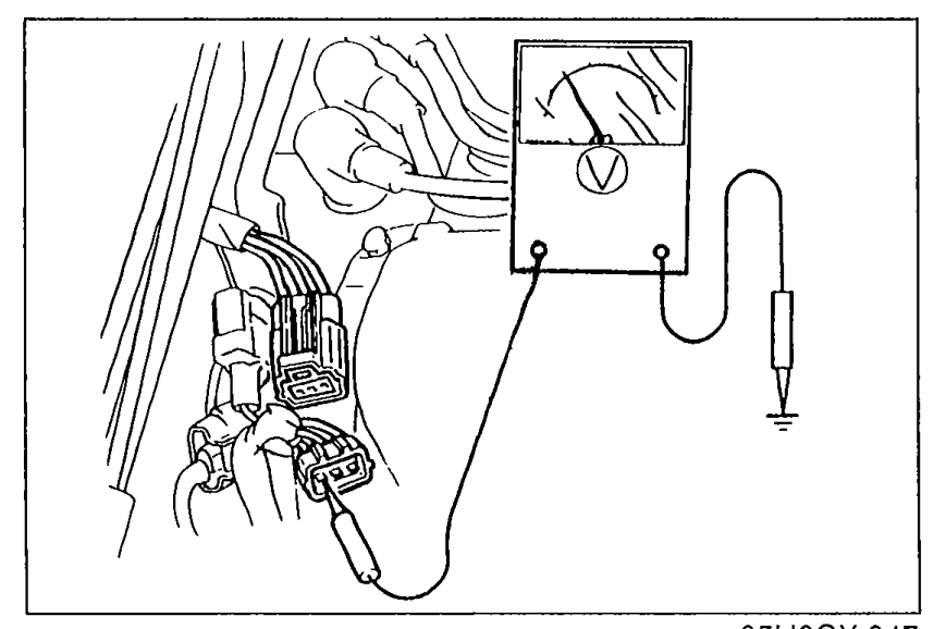 Engine bay photo: voltmeter probes connected to the positive (+) terminal of the ignition coil connector to verify approx. 12V with ignition switch ON.