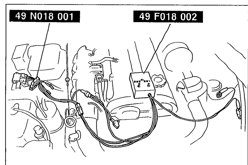 Engine bay photo showing the 49 N018 001 Adapter harness and 49 F018 002 Igniter checker SSTs connected between the igniter and the igniter connector.