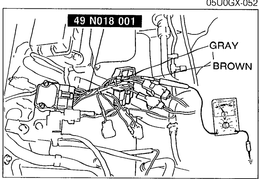 Engine bay photo showing 49 N018 001 adapter harness with voltmeter probes connected between the GRAY and BROWN wires of the SST to verify approx. 12V.