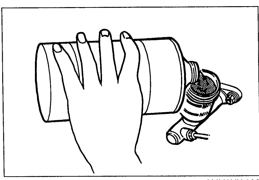 Illustration of a hand drawing fluid from the clutch master cylinder reserve tank with a suction pump.