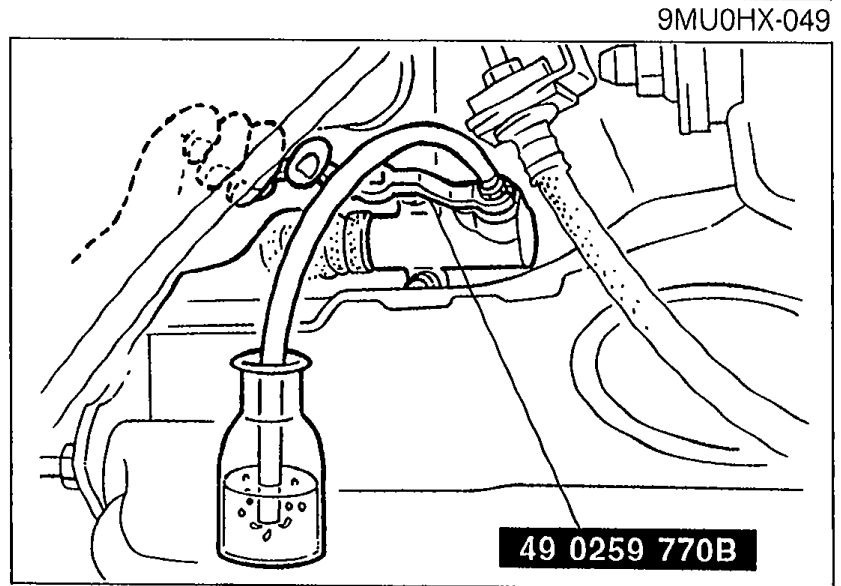 Photo showing the SST 49 0259 770B attached to the clutch release cylinder bleeder screw with a vinyl hose running into a clear container holding clutch fluid.