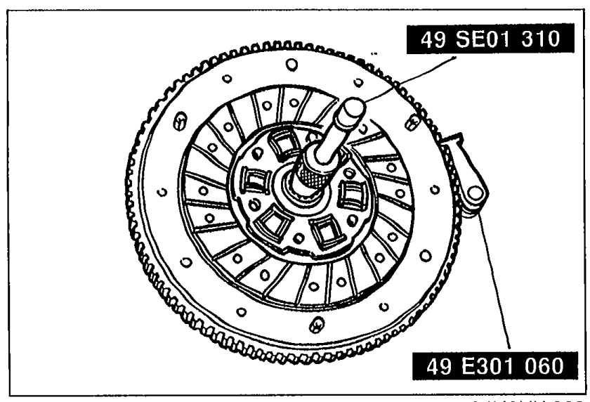 Clutch disc installation. Disc held in flywheel with SST 49 SE01 310 (centering tool) labeled at top and 49 E301 060 labeled at bottom of the SST.