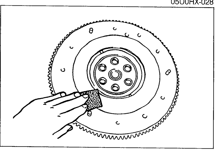 Flywheel ring-gear teeth being cleaned/inspected with a wire brush. Shows the contact surface and ring gear teeth.