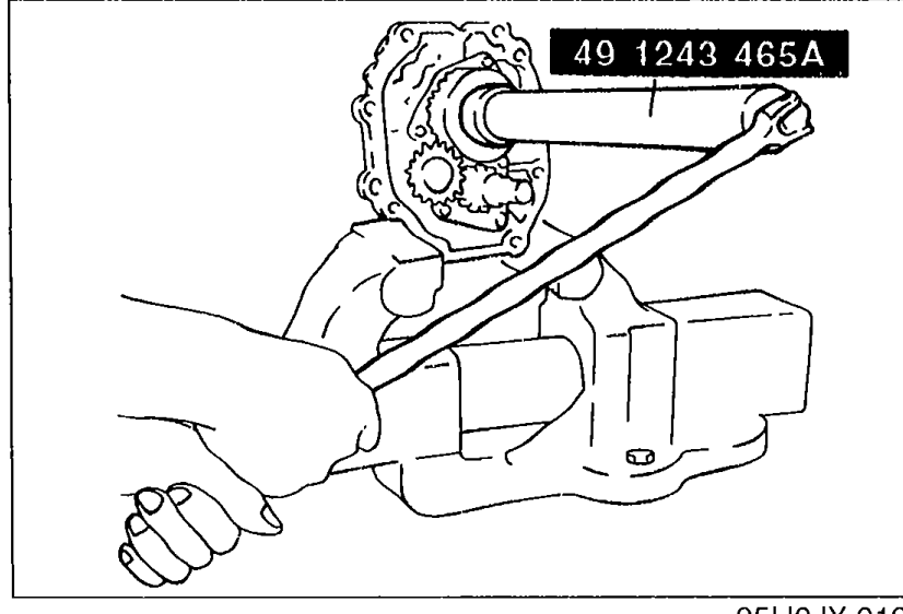 Locknut removal using SST 49 1243 465A (wrench/holder). Hands apply force via the SST to uncrimp/remove the mainshaft locknut while the assembly is held in a vise.
