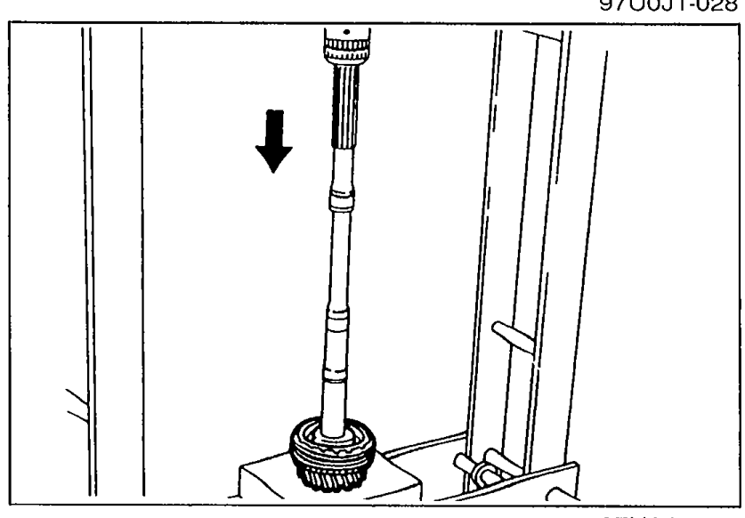 Photograph showing the mainshaft being pressed vertically (downward arrow shown) out of the clutch hub assembly using a press.