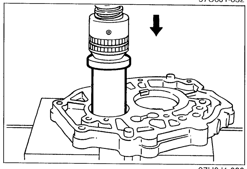 Photograph showing the countershaft center bearing being pressed out of the bearing housing using a suitable pipe. Downward arrow indicates press direction.