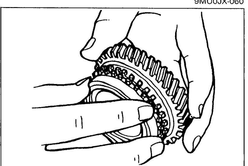 Hands holding a synchronizer ring while inspecting the individual ring teeth and the taper surface for wear and cracks.