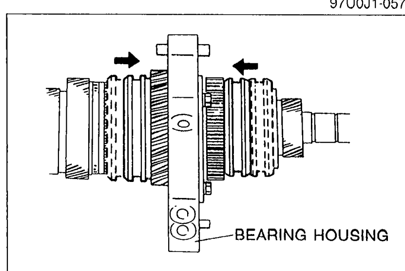 Bearing housing secured in a vise with arrows showing the direction to slide the clutch hub sleeves onto 1st and reverse gears to lock the mainshaft. Label indicates BEARING HOUSING.