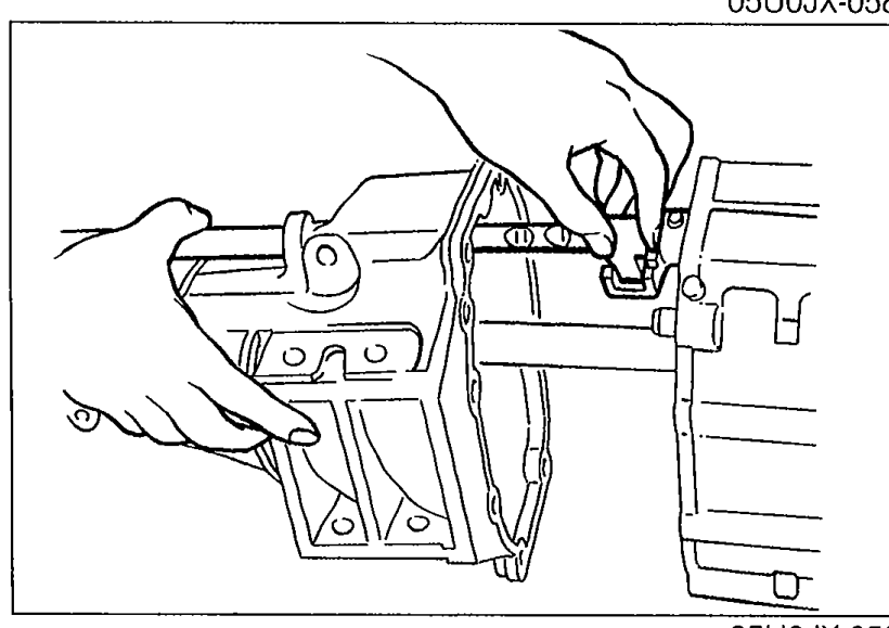 Extension housing being installed onto the transmission case with hands shown aligning the inner shift lever and shift rod end groove.