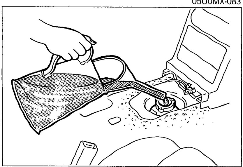 Photo of a hand pouring oil from a flexible funnel into the change control case opening on top of the transmission tunnel.