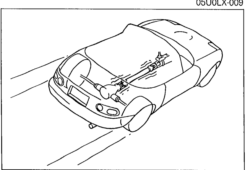Three-quarter front-side view illustration of the MX-5 / Miata roadster with the underbody propeller shaft / drivetrain shown semi-transparently underneath, illustrating the test drive verification step.