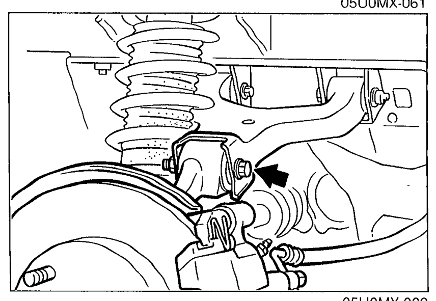 Under-vehicle view of the upper arm installation bolt/nut location with an arrow indicating the installation point.