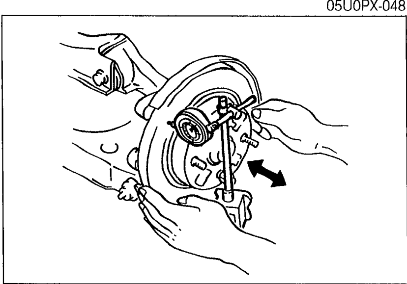 Illustration of measuring rear disc plate (rotor) runout with a dial indicator mounted on the rear suspension, with the probe contacting the outer edge of the disc plate surface. Arrow shows runout direction.