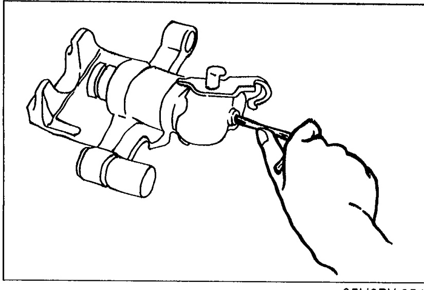 Illustration showing a hand using an Allen wrench to turn the adjustment gear counterclockwise on the caliper to pull the piston in fully during assembly.