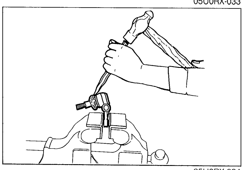 Chisel being used to remove the ball joint dust boot. Hand holding chisel against the boot/ball joint.
