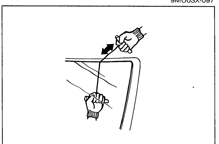 Two people sawing the piano wire around the perimeter of the windshield; one hand grips a tee bar on each end of the wire. Illustrates the sawing motion called out in steps 4-5.
