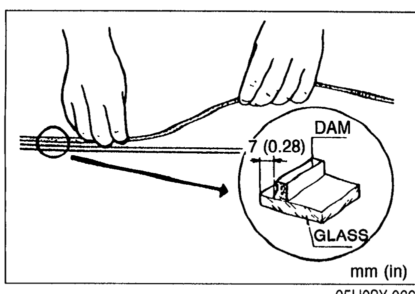 Hands bonding a new DAM along the circumference of the windshield GLASS at 7 mm (0.28 in) from the edge. An inset detail at right shows the DAM bonded to the GLASS with the 7 (0.28) mm dimension.
