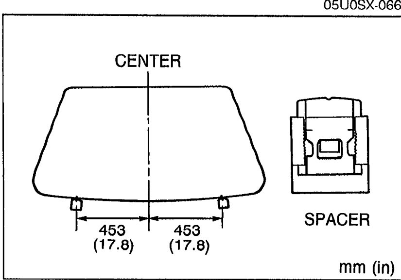 Top view of the windshield showing where the two SPACER blocks attach at the bottom edge, located 453 mm (17.8 in) to either side of CENTER. An enlarged view of the spacer is shown at right.
