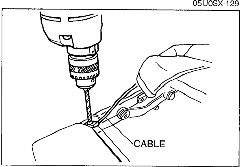 Drill being used on the link assembly to remove rivets; the CABLE is called out at the bottom.