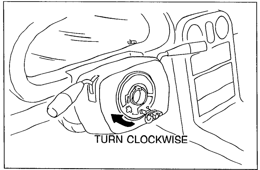 Photo showing technician's hand turning clock spring connector clockwise. Caption 'TURN CLOCKWISE'.