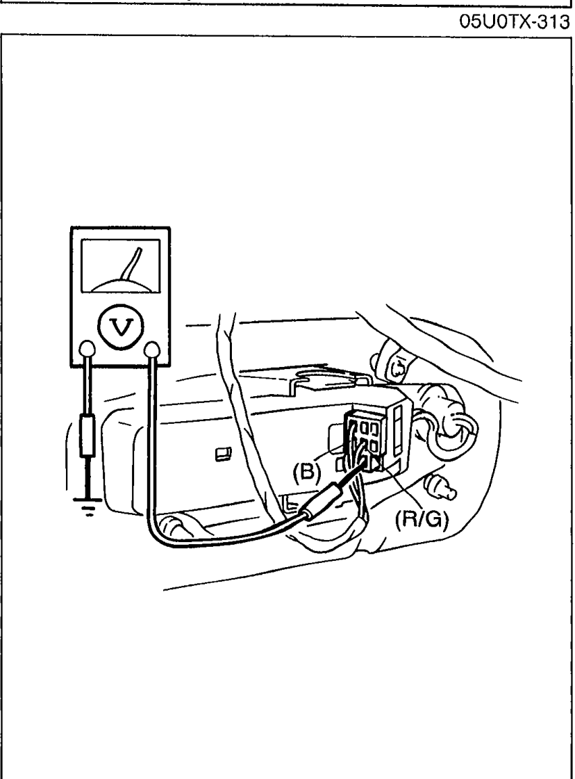 Voltmeter being applied to back-up light connector wires labeled (R/G) and (B), measuring voltage at the terminal-wires of the back-up light connectors.